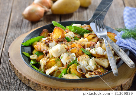 Fried potatoes with halibut fillet, sugar peas and onion rings, often served in a frying pan 81369859
