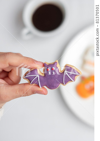 woman hand holding funny Halloween Cookie during drinking coffee. Happy Halloween day, Trick or Threat, Hello October, fall autumn, Traditional, party and holiday concept 81370501