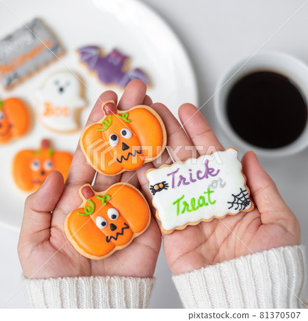 woman hand holding funny Halloween Cookie during drinking coffee. Happy Halloween day, Trick or Threat, Hello October, fall autumn, Traditional, party and holiday concept 81370507