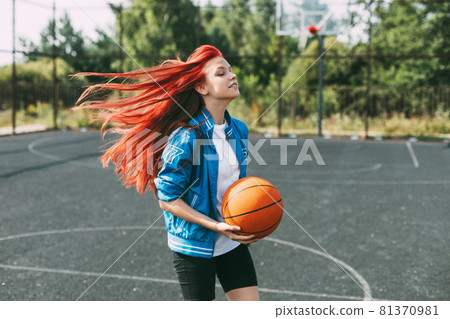 A young basketball player is training on an outdoor basketball court, a teenage girl is playing basketball. Basketball, sports A young basketball player is training on an outdoor basketball court, a teenage girl is playing basketball. Basketball, sports 81370981