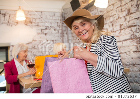 Cheerful senior females with shopping bags looking happy Cheerful senior females with shopping bags looking happy 81372637