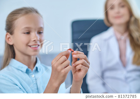 Girl holding hearing aid in her hands 81372785