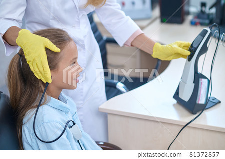Pleased girl having her hearing checked on the audiometer Pleased girl having her hearing checked on the audiometer 81372857