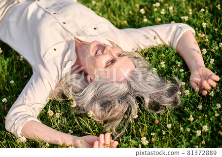 Smiling woman lying on blooming grass 81372889