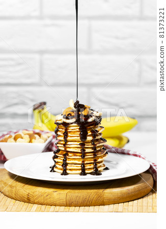 Pancakes with Chocolate Syrup, Nuts and Bananas. Stack of whole flapjack. Chocolate Being Poured Into Slapjack, Tasty breakfast and Healthy Food 81373221