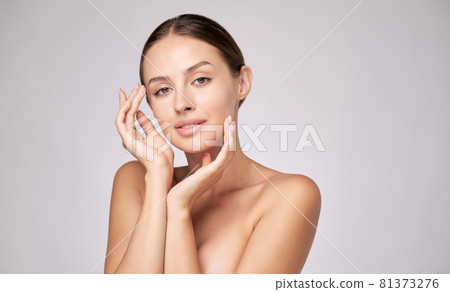 Beautiful Young Woman with Clean Fresh Skin standing over light grey background Beautiful Young Woman with Clean Fresh Skin standing over light grey background 81373276