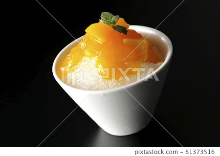 在黑色背景上拍攝了帶有大量芒果糖漿的刨冰和果肉 在黑色背景上拍攝了帶有大量芒果糖漿的刨冰和果肉 81373516
