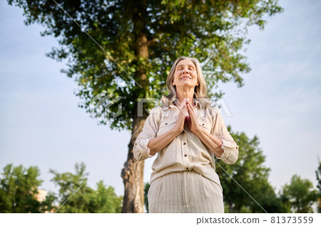 Smiling woman holding palms in front of her Smiling woman holding palms in front of her 81373559