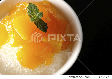 A bird's-eye view of shaved ice with plenty of mango syrup containing pulp on a black background 81373574