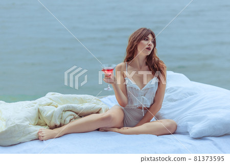 Woman with a glass of wine on the bed. Woman with a glass of wine on the bed. 81373595