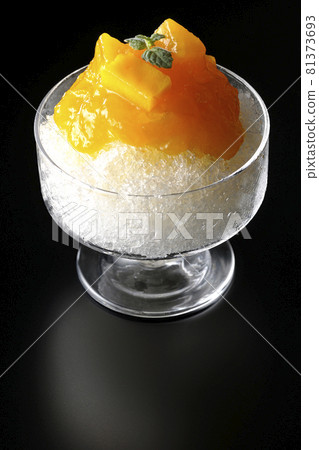 Photographed shaved ice with plenty of mango syrup with pulp on a black background Photographed shaved ice with plenty of mango syrup with pulp on a black background 81373693