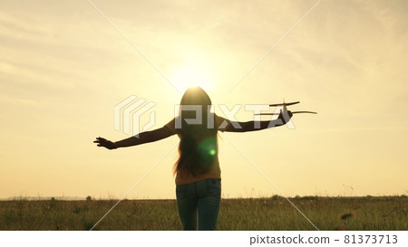 Child dreams of being a pilot of an airplane flying in the sky to the sun, the kid runs into the sunset, loves jogging in nature, the girl plays in the open air, feels the freedom of playing the game Child dreams of being a pilot of an airplane flying in the sky to the sun, the kid runs into the sunset, loves jogging in nature, the girl plays in the open air, feels the freedom of playing the game 81373713