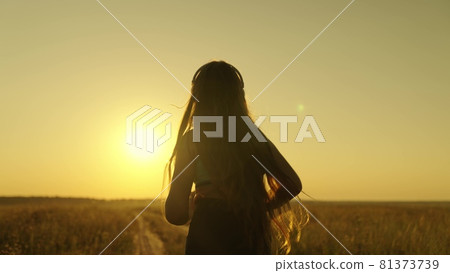 Happy girl runs in headphones at sunset, an active lifestyle for losing weight and maintaining a slim figure, a woman striving for the dream of being the first, preparing for a running competition 81373739