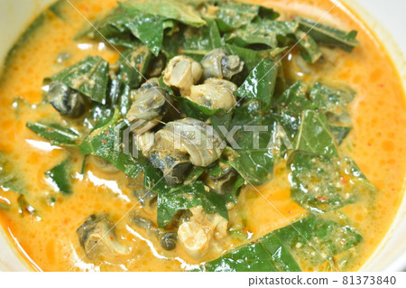 spicy boiled cockle with acacia and basil leaf in red curry coconut milk soup in bowl 81373840