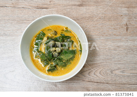 spicy boiled cockle with acacia and basil leaf in red curry coconut milk soup in bowl spicy boiled cockle with acacia and basil leaf in red curry coconut milk soup in bowl 81373841
