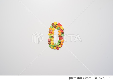 Numeral zero from sweet pastry topping in the form of colorful foliage on a white background. Numeral zero from sweet pastry topping in the form of colorful foliage on a white background. 81373908