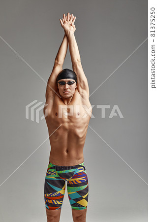 A swimmer in swimming trunks prepares for the start, an athlete on a gray background prepares for a swim, I take a pose for a swim in the pool, wearing glasses and a mask. A swimmer in swimming trunks prepares for the start, an athlete on a gray background prepares for a swim, I take a pose for a swim in the pool, wearing glasses and a mask. 81375250