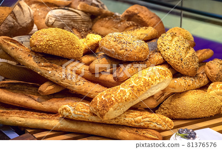 Delicious loaves of bread in baker shop. Different types of bread loaves on bakery shelves. Delicious loaves of bread in baker shop. Different types of bread loaves on bakery shelves. 81376576