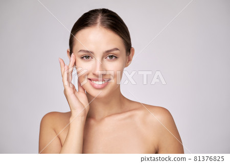 Beautiful Young Woman with Clean Fresh Skin standing over light grey background Beautiful Young Woman with Clean Fresh Skin standing over light grey background 81376825