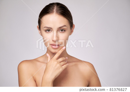 Beautiful Young Woman with Clean Fresh Skin standing over light grey background Beautiful Young Woman with Clean Fresh Skin standing over light grey background 81376827
