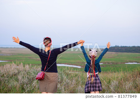 Mother and daughner on a hill with raised hands up to the sky. Happy family concept. T Mother and daughner on a hill with raised hands up to the sky. Happy family concept. T 81377849