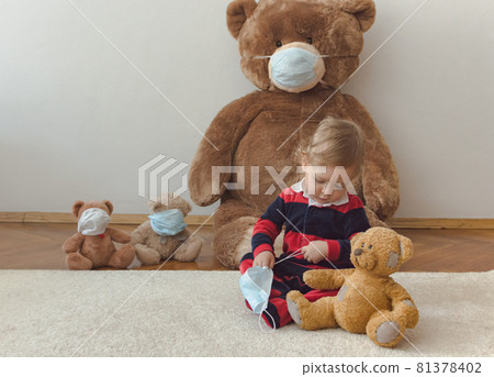 Child playing with his sick teddy bears wearing medical mask against viruses. Role playing, child playing doctor with plush toy. Children and illness concept. Child playing with his sick teddy bears wearing medical mask against viruses. Role playing, child playing doctor with plush toy. Children and illness concept. 81378402
