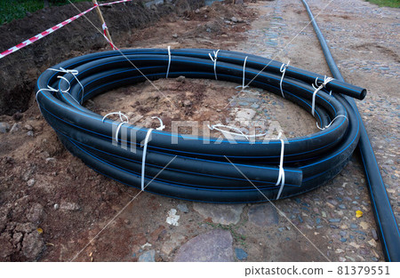 A circle of black plastic pipe lies on the ground. The concept of communications A circle of black plastic pipe lies on the ground. The concept of communications 81379551