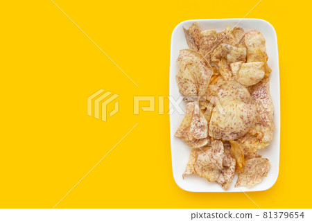 Crispy taro chips in white plate on yellow background. 81379654