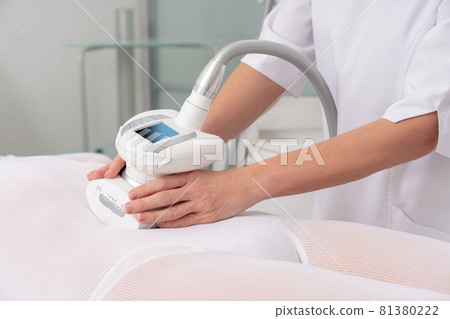 Woman in special white suit getting anti cellulite massage in a spa salon. LPG, and body contouring treatment in clinic. Woman in special white suit getting anti cellulite massage in a spa salon. LPG, and body contouring treatment in clinic. 81380222