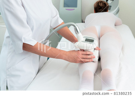 Woman in special white suit getting anti cellulite massage in a spa salon. LPG, and body contouring treatment in clinic. Woman in special white suit getting anti cellulite massage in a spa salon. LPG, and body contouring treatment in clinic. 81380235
