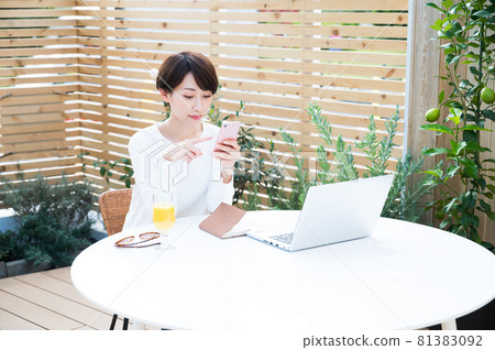 一位在戶外工作時使用智能手機的女性 一位在戶外工作時使用智能手機的女性 81383092