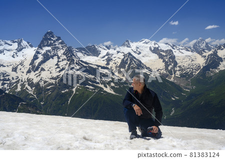 A man in the mountains took off his hat and knelt on a snowy peak, bowing to the beauty of mountains A man in the mountains took off his hat and knelt on a snowy peak, bowing to the beauty of mountains 81383124