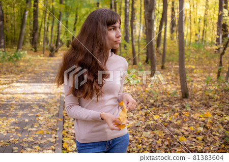 young beautiful woman with autumn leaf smiling in autumn park in sun shines.happy young woman young beautiful woman with autumn leaf smiling in autumn park in sun shines.happy young woman 81383604