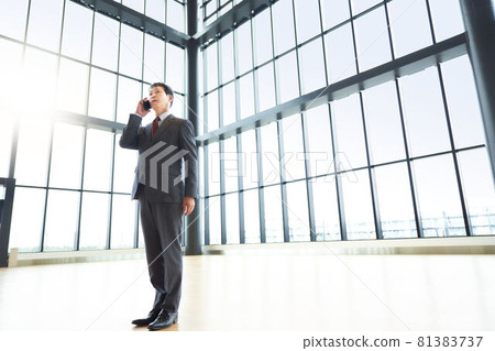 A businessman who puts his smartphone on his ear and makes a call A businessman who puts his smartphone on his ear and makes a call 81383737