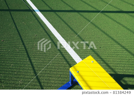 Outdoor sport playground with rubberized ground. Yellow bench on a green sport field. Physical Culture school lesson. Sport background for poster, wallpaper or banner 81384249
