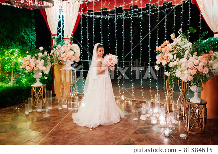 bride with bouquet of flowers in night park against background of garland. bride with bouquet of flowers in night park against background of garland. 81384615