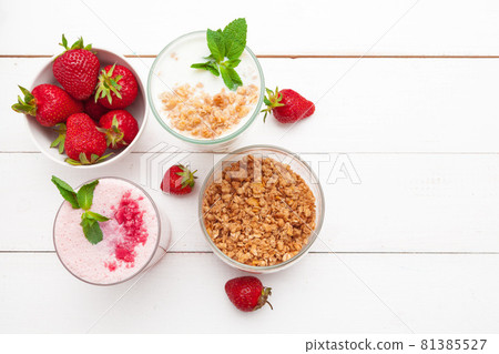 Healthy breakfast with yoghurt, granola and strawberries on white wooden background top view Healthy breakfast with yoghurt, granola and strawberries on white wooden background top view 81385527