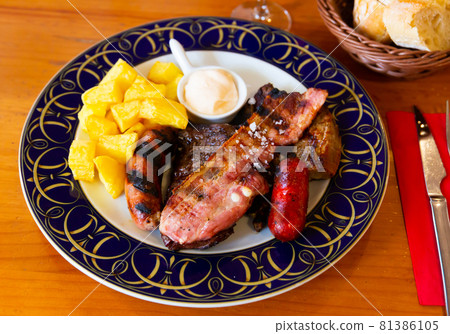 Grilled sausages and pork with potatoes and sauce Grilled sausages and pork with potatoes and sauce 81386105