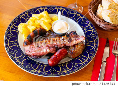Broiled meat and sausages with potatoes and sauce 81386153