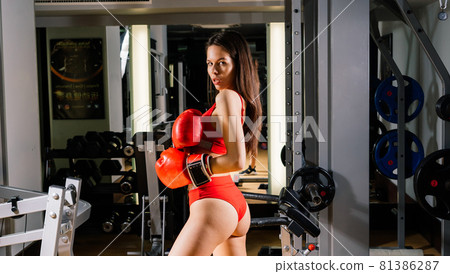 Seductive boxer model wearing big gloves and posing in fitness gym 81386287