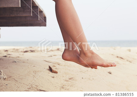 Woman's legs sitting and relax at beach jetty in summer 81386555
