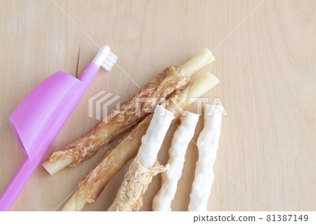 Dog dental gum and toothbrush on a wood grain background Dog dental gum and toothbrush on a wood grain background 81387149