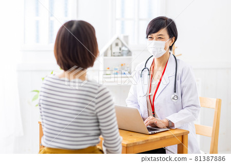 Image of a female doctor wearing a mask doing a medical examination Image of a female doctor wearing a mask doing a medical examination 81387886
