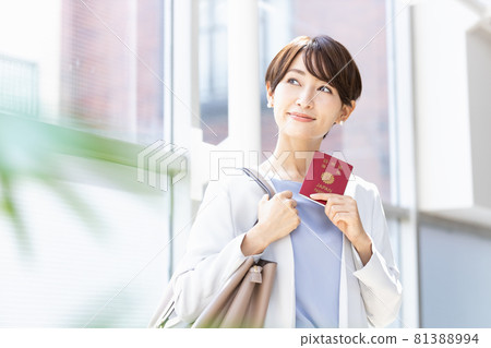 Woman standing by a bright window with a passport 81388994