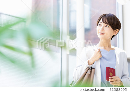 拿著護照站在明亮的窗戶旁的女人 81388995