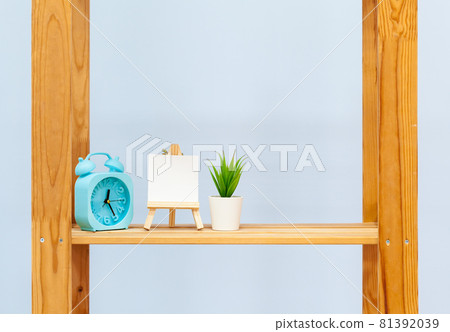 Wooden shelf with alarm clock and objects against blue background Wooden shelf with alarm clock and objects against blue background 81392039