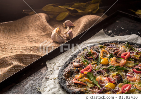 Italian pizza with black dough and seafood on a baking tray from the oven Italian pizza with black dough and seafood on a baking tray from the oven 81392410