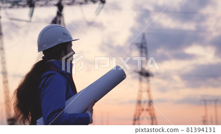 An electrician at a high voltage power plant works with a project at sunset in the sky, electrical energy design, industry concept, modern business technology, an engineer in the glare of the sun 81394131