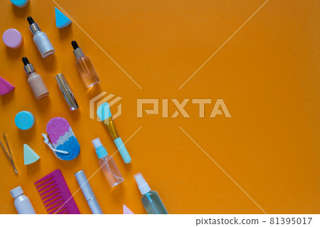 Flat composition with cosmetic products on an orange background. Multicolored sponges. Women's self-care. Top view image with copy space. Flat composition with cosmetic products on an orange background. Multicolored sponges. Women's self-care. Top view image with copy space. 81395017