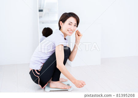 A middle-aged woman who is happy to weigh after training A middle-aged woman who is happy to weigh after training 81395208
